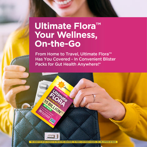 View 5 A young woman smiles as she places an Ultimate Flora Probiotic Go Pack into her black handbag.